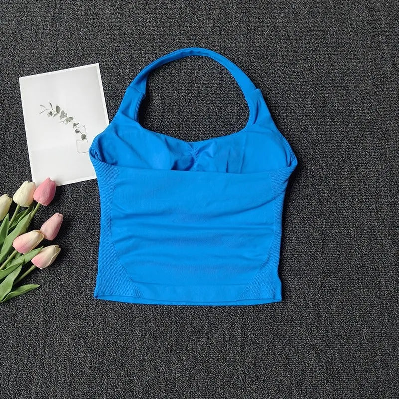 Haut sans bretelles bleu vif, unis, pour le yoga et la fitness, posé sur fond gris foncé à côté de tulipes roses.
