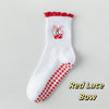 Weiße Stricksocken mit rotem Spitzenrand und roter Schleife.
