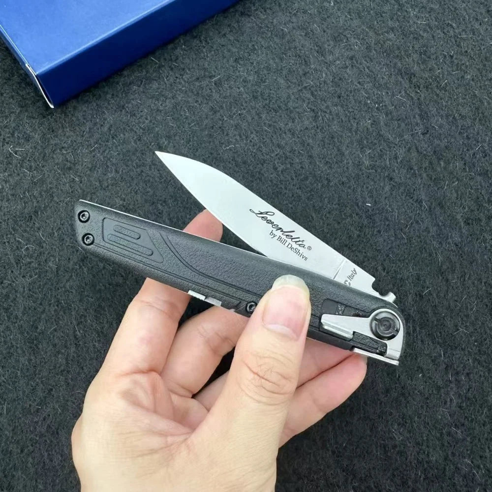 A hand holds a black precision folding pocket knife with a silver blade and white label against a dark gray background.