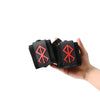 Une main tient un paire de bandes de poignet noires avec un motif d'éclair rouge stylisé.