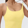 A model wearing a yellow women's athletic crisscross tank top, showing the upper body view.