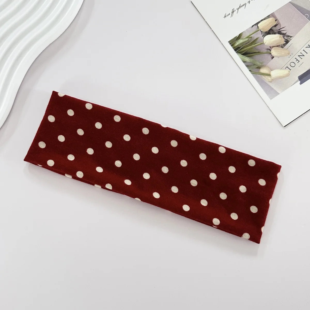 Bandeau de yoga élastique à pois marron sur une surface blanche.