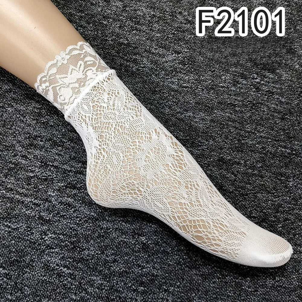 Nahaufnahme eines weißen floralen Spitzen-Knöchelsockes auf einem Fuß vor dunkelgrauem Hintergrund.