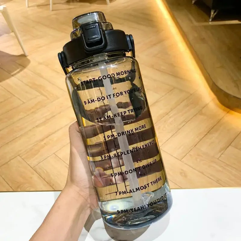 Une bouteille d'eau sportive transparente avec des marqueurs de temps, tenue contre un fond en bois.