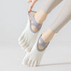 A close-up of a person wearing light gray five-finger invisible yoga and fitness socks on their foot.