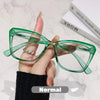 Eine Hand hält eine grüne photochromische multifokale Brille vor einem weißen Hintergrund.