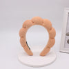 A light peach colored sponge terry cloth headband for hair styling.