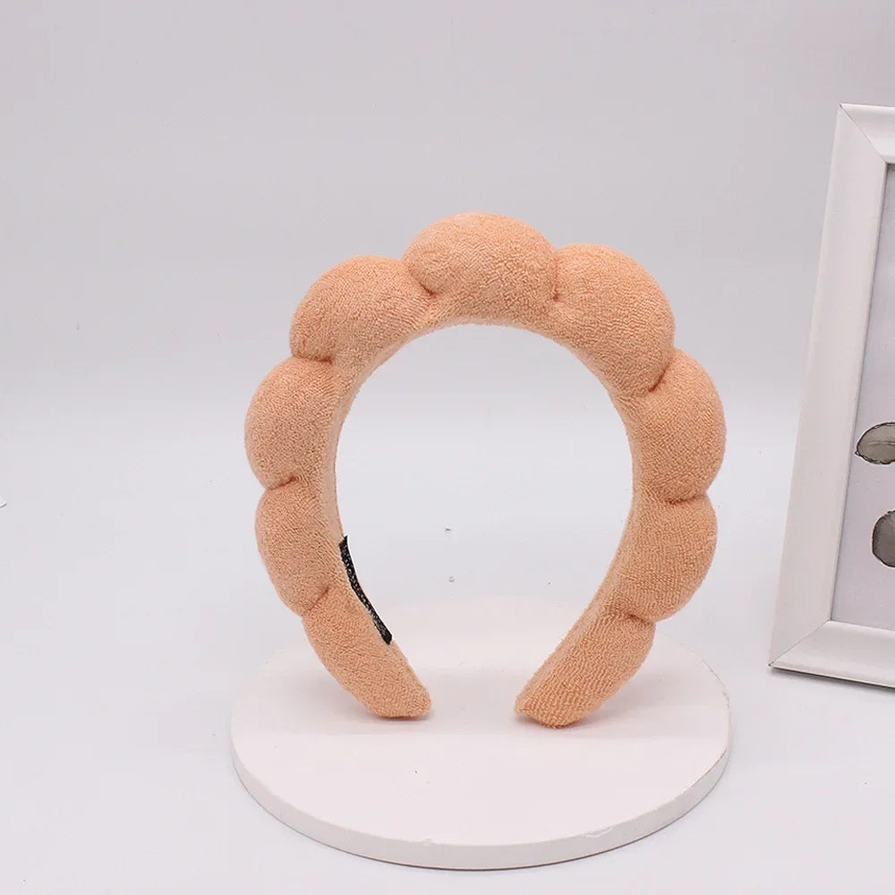 A light peach colored sponge terry cloth headband for hair styling.