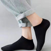 Un par de calcetines de barco negros puestos en un pie, combinados con pantalones gris claro.