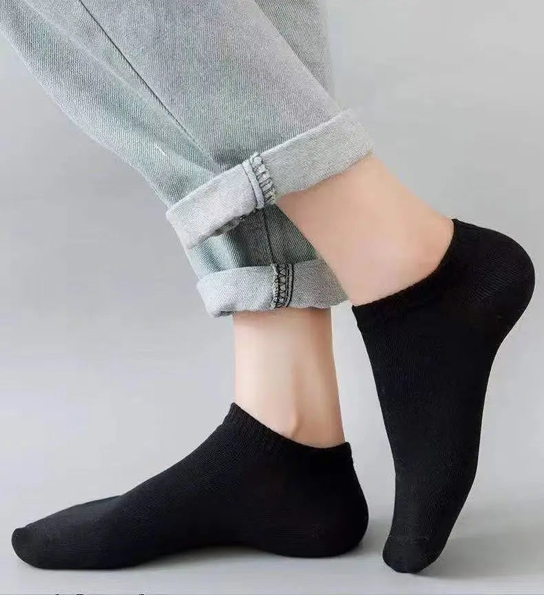 Un par de calcetines de barco negros puestos en un pie, combinados con pantalones gris claro.