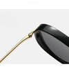 A pair of black fashion protective sunglasses with gold-toned arms shown in a profile view.