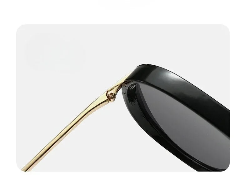 A pair of black fashion protective sunglasses with gold-toned arms shown in a profile view.
