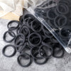 A pile of black elastic hair bands in a clear plastic bag on a gray surface.