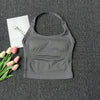 A gray seamless yoga and pilates sports bra is displayed on a dark gray textured surface next to pink and white tulips.