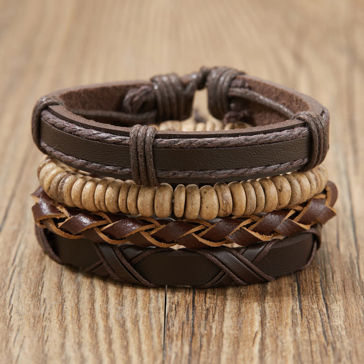 Stapel handgemachter Lederblatt-Feder-Armbänder in verschiedenen Braun- und Beigetönen auf einer Holzoberfläche