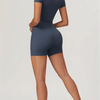 A woman wearing a dark blue seamless yoga jumpsuit, shown from the back and side.