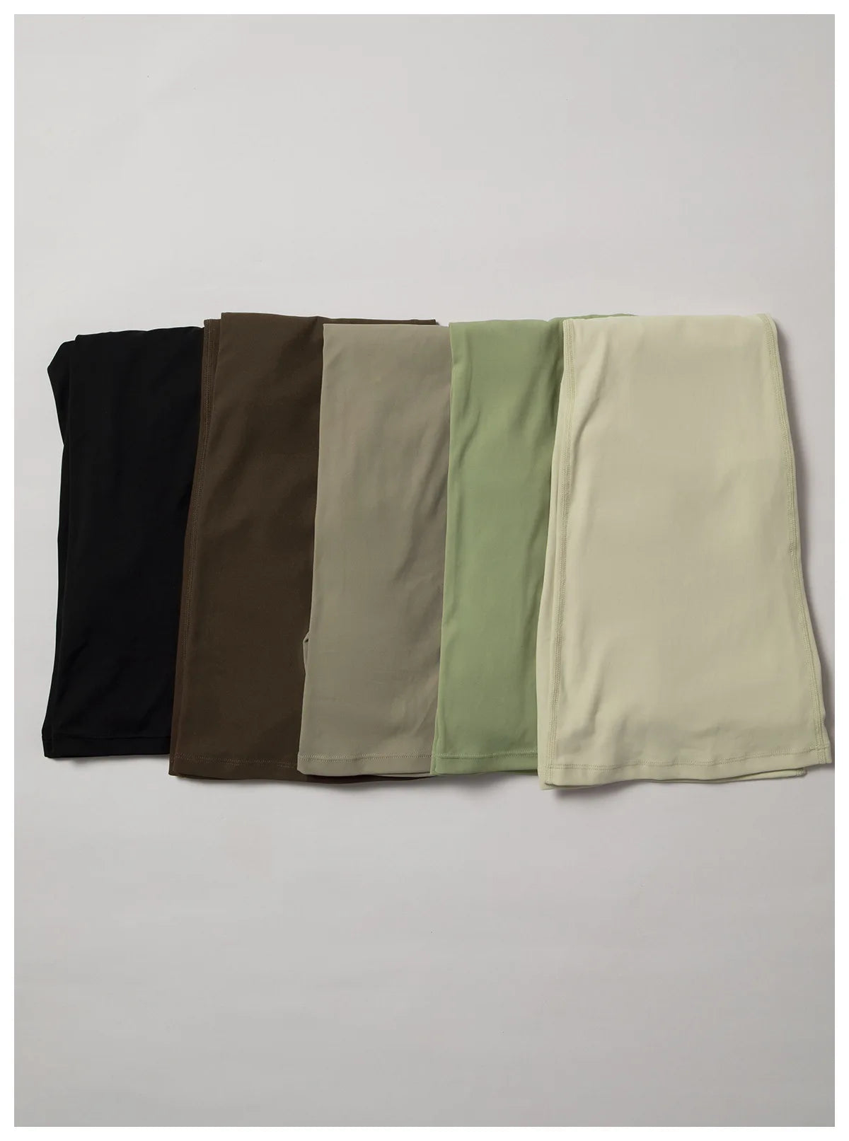 A set of five women's performance tracksuits in black, olive green, beige, and light green.