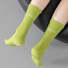 Ein Paar leuchtend grüne, atmungsaktive Anti-Rutsch-Yoga- und Fitnesssocken auf dem Bein eines Menschen.