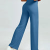 A woman is modeling high waisted blue yoga pants while standing.