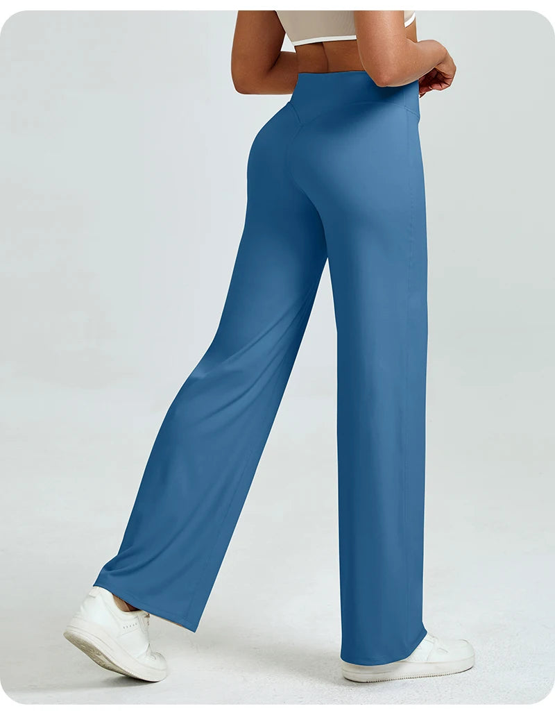A woman is modeling high waisted blue yoga pants while standing.