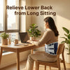A woman is sitting at a desk using a laptop while wearing an adjustable lumbar support back brace.