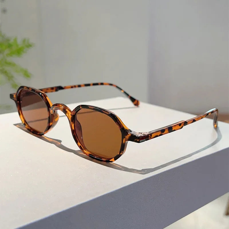 Vintage oval sunglasses with brown leopard print frames and amber lenses resting on a white surface.