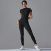 A model wearing a black Naked Zipper Yoga Jumpsuit standing against a gray background.