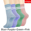 Cuatro pares de calcetines de yoga y pilates sin deslizamiento para mujer en azul, morado, verde y rosa.