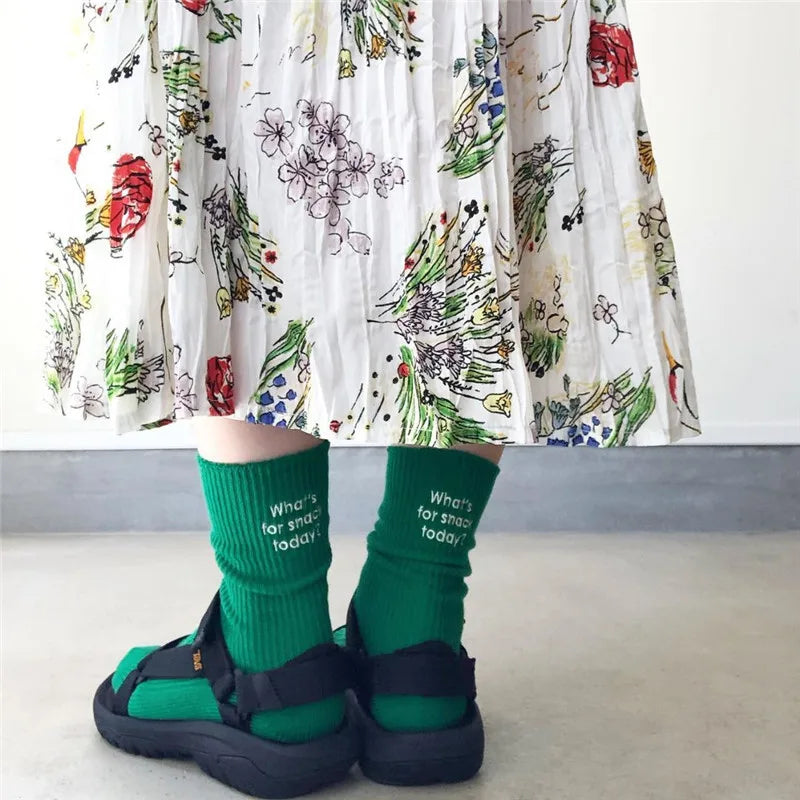 A pair of green embroidered cotton socks worn by a person, displayed against a light background.