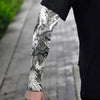 Close-up of a person wearing black clothing with an intricate gray and white dragon design on the forearm.