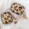 A leopard print protective case for AirPods Pro featuring gold accents and a pearl charm.