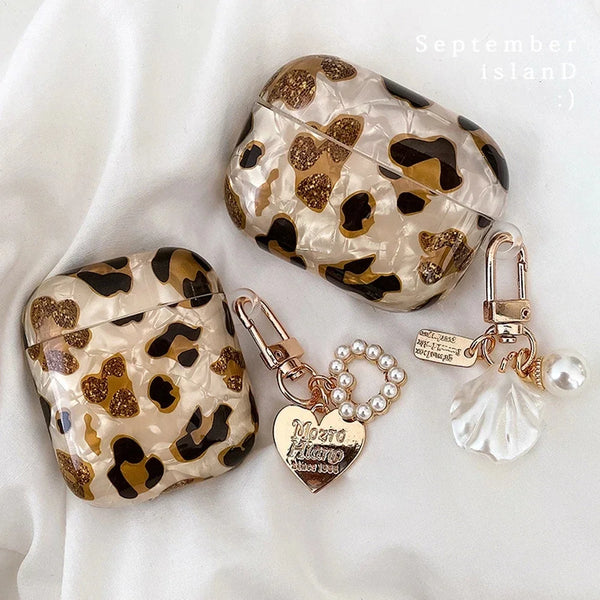 A leopard print protective case for AirPods Pro featuring gold accents and a pearl charm.