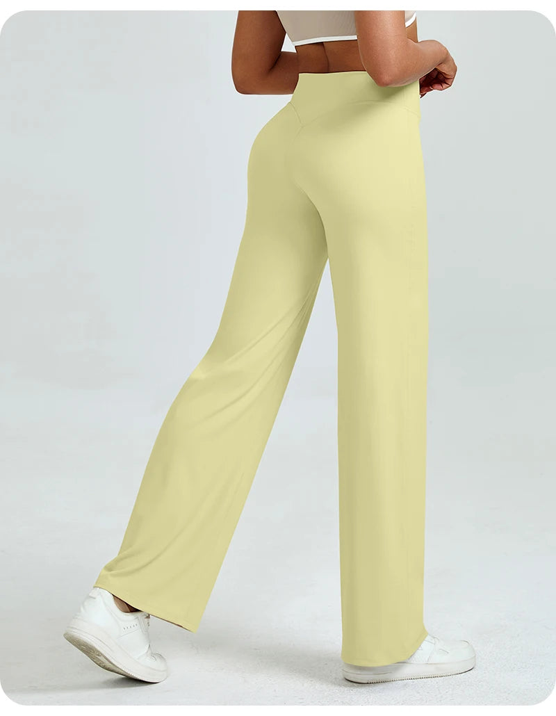 A woman is modeling light yellow high waisted yoga pants while standing.