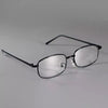 A pair of clear eyeglasses with a retro square frame resting on a white surface.
