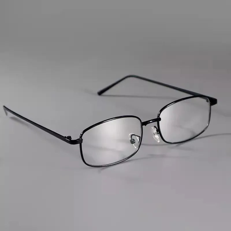 A pair of clear eyeglasses with a retro square frame resting on a white surface.