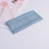 A light blue knitted headband is shown resting on a white surface next to a piece of paper.