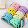 A collection of 50 mixed color elastic hair bands arranged in a wooden box.