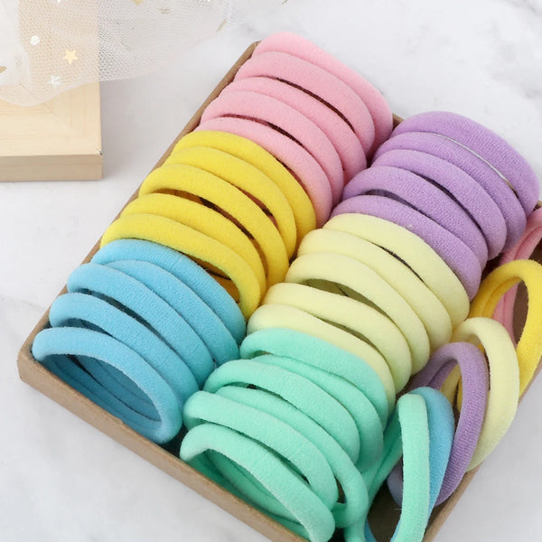 Una colección de 50 bandas elásticas de cabello de colores mezclados, dispuestas en una caja de madera.