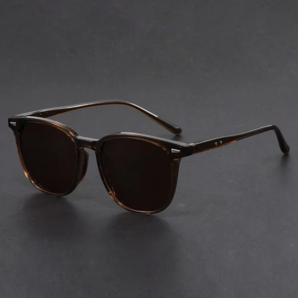Brown tinted square sunglasses with thin metal arms resting on a dark surface.