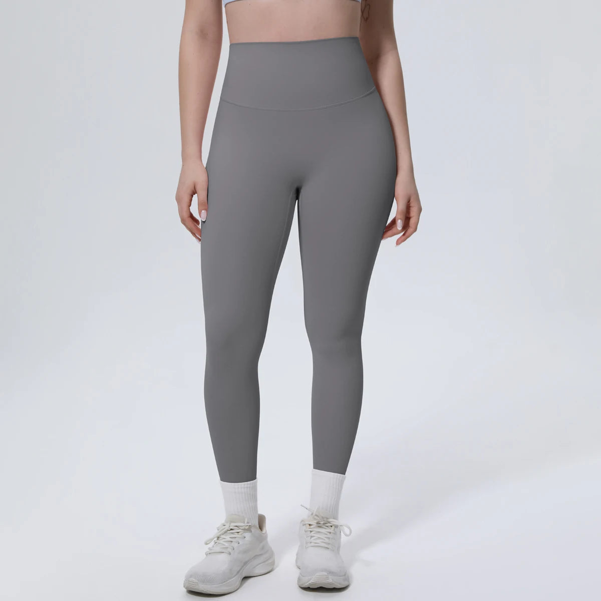A model is wearing high-waisted gray quick-drying yoga and fitness leggings and white athletic shoes.