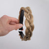 A hand is braiding a blonde hair extension into a twisted braid using a black elastic band.