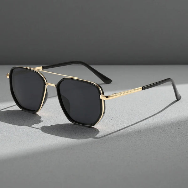 Gold-rimmed sunglasses with black lenses resting on a gray surface.