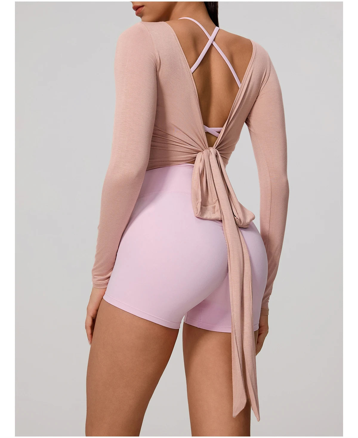 A woman wearing a long sleeve top and matching shorts in a dusty rose color, featuring a tie-front detail.