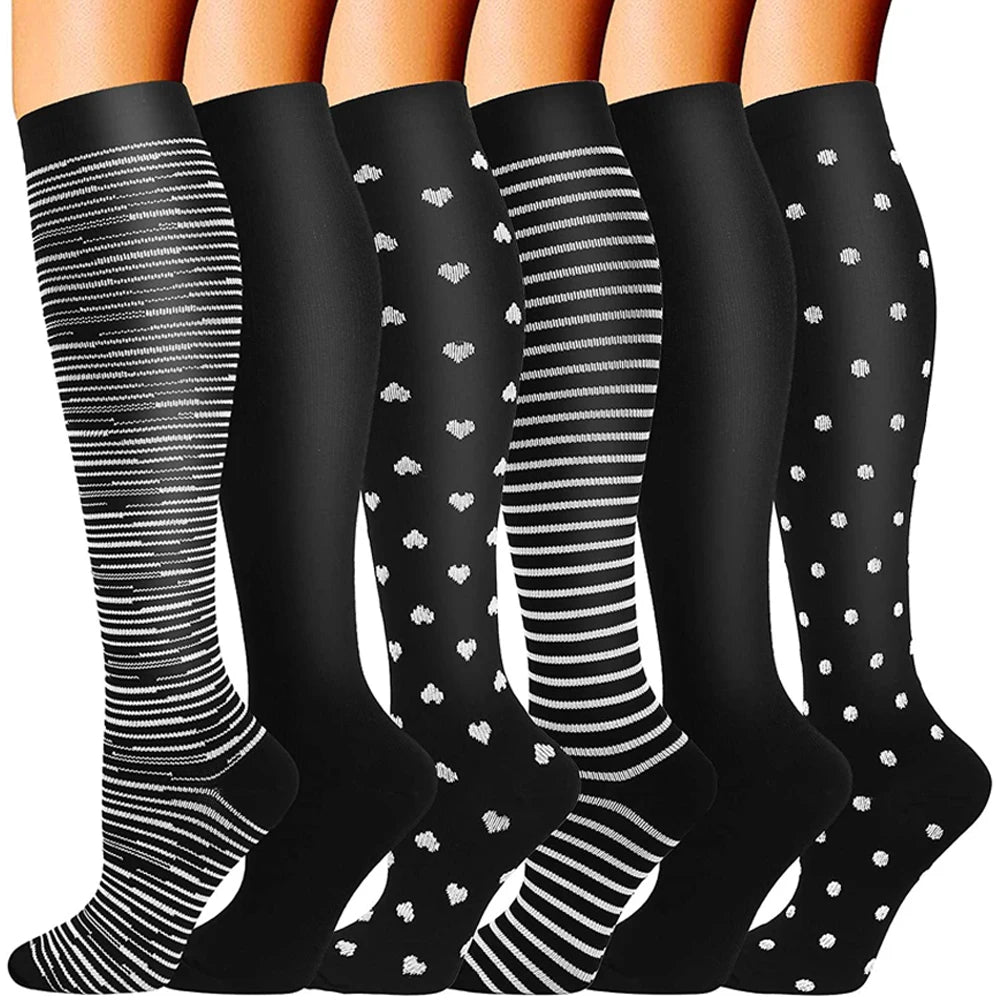 A pair of black compression socks with white stripes and polka dots shown from the ankle up.