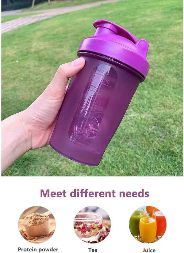 Une main tient une bouteille de sport étanche violette avec des graduations, à côté de poudre de protéines, de thé et de jus