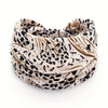 A close-up of a beige and black leopard print fabric headband rolled into a coil.