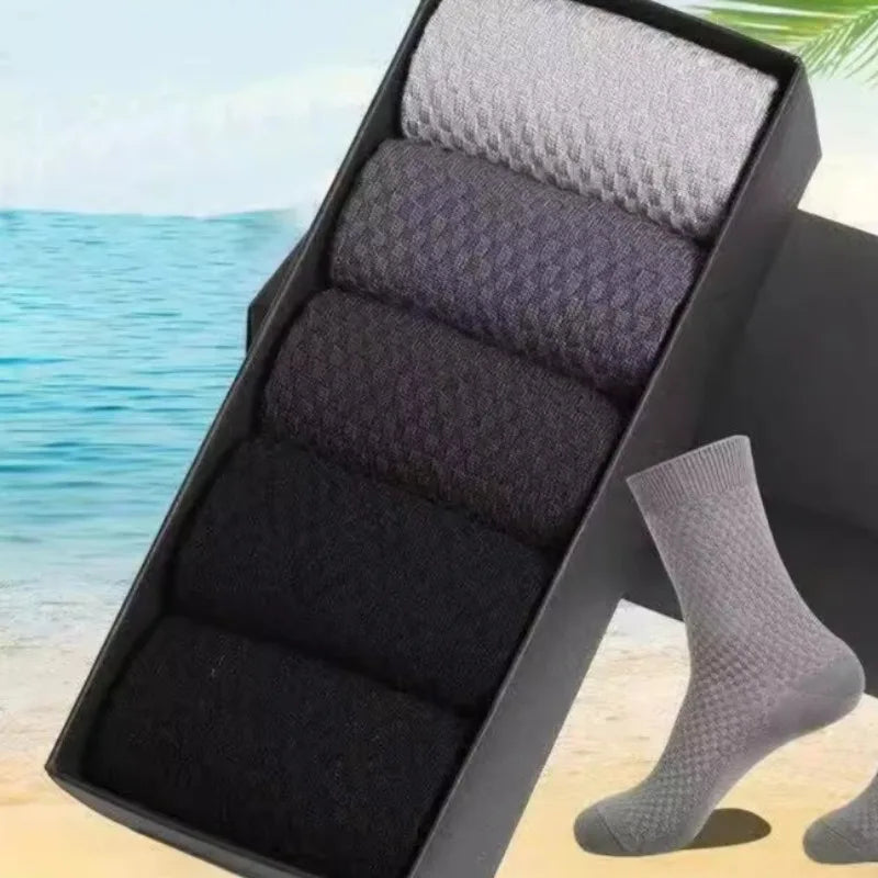 A black storage box filled with grey and black bamboo fibre anti-odor socks on a sandy surface.