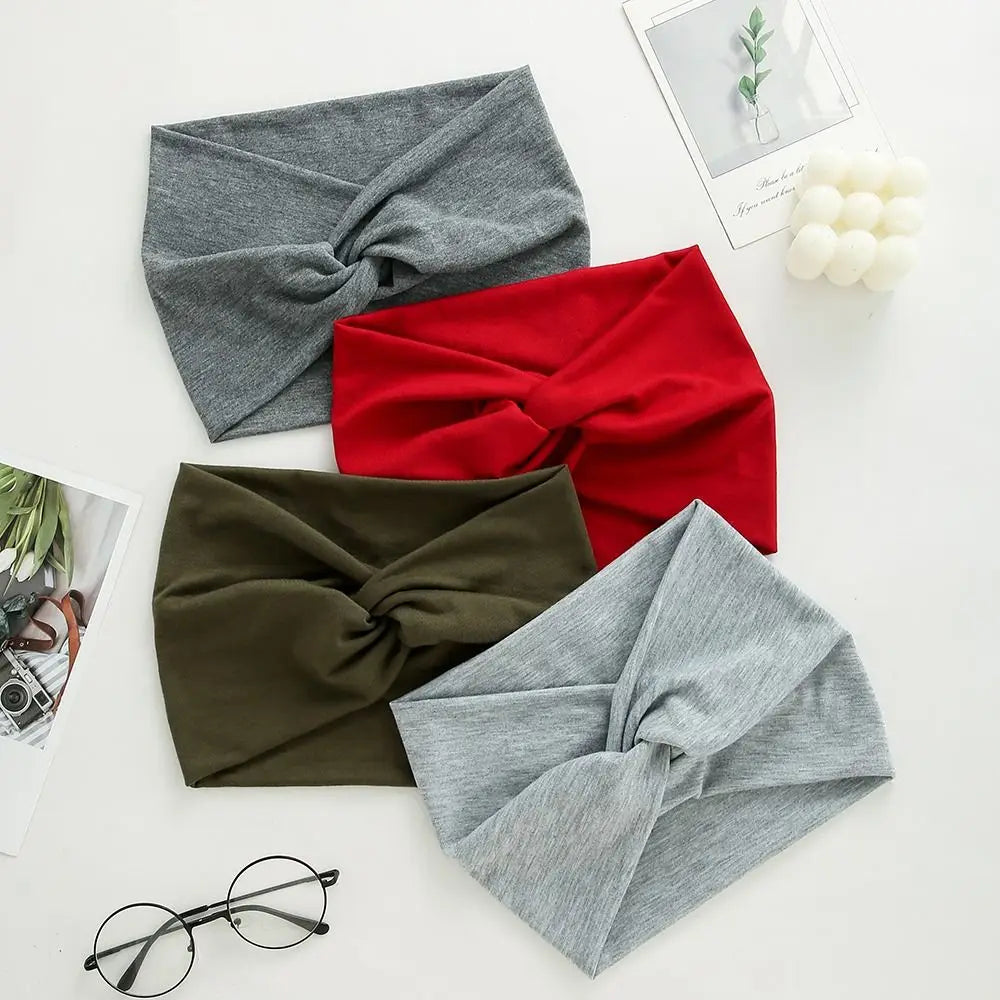 Three knitted fabric headbands in gray, red, and olive green are displayed on a white surface.