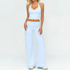 A woman wearing a white women's premium fitness tracksuit consisting of a cropped top and loose-fitting pants.