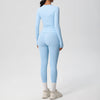 A woman wearing a light blue long-sleeved performance yoga set consisting of a long-sleeved top and leggings.
